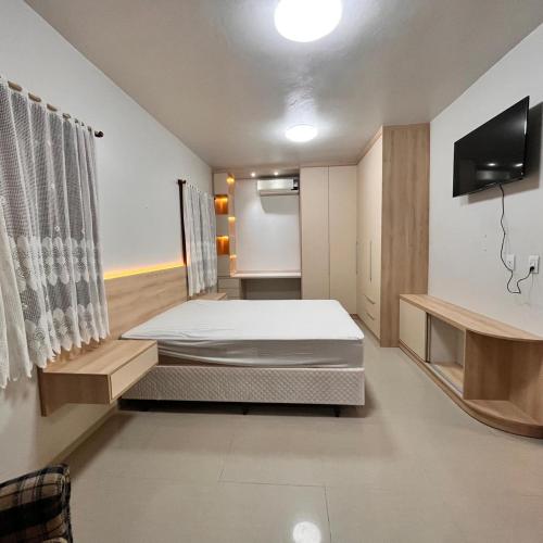 a bedroom with a bed and a tv on a wall at Casa do vivi 1 in Tramandaí
