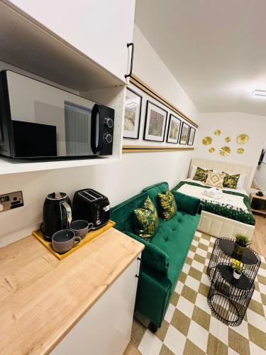 a living room with a green couch and a bed at Luxurious Private Room with Kitchenette near QE Hospital Harborne R5 in Birmingham