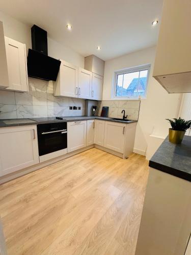 a kitchen with white cabinets and a wooden floor at Luxurious Private Room with Kitchenette near QE Hospital Harborne R5 in Birmingham