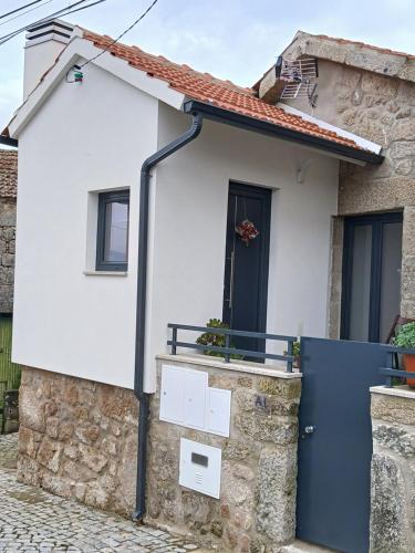 a house with a blue door and a stone wall at Cantinho da Fonte in Calvos