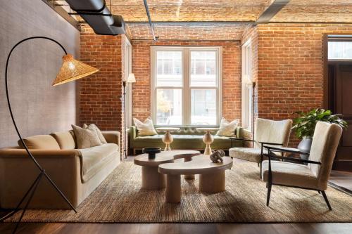 a living room with a couch and chairs and a brick wall at Arlo Washington DC in Washington