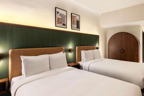 two beds in a hotel room with green walls at Arlo Washington DC in Washington