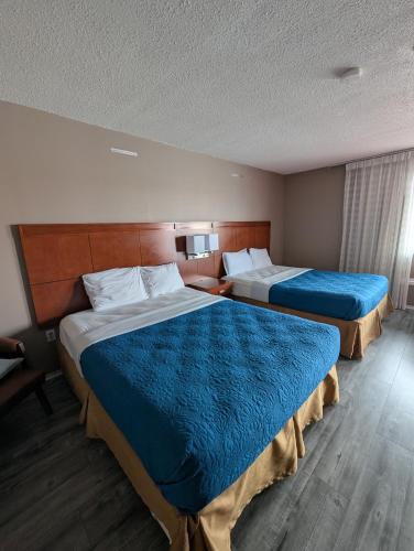 a hotel room with two beds with blue blankets at 7 Nights Stay in Niagara Falls