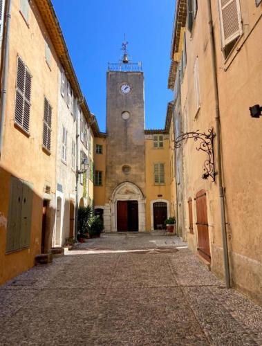 Une allée avec un bâtiment doté d'une tour d'horloge dans l'établissement BIOT-Charmant et coquet F2, à Biot