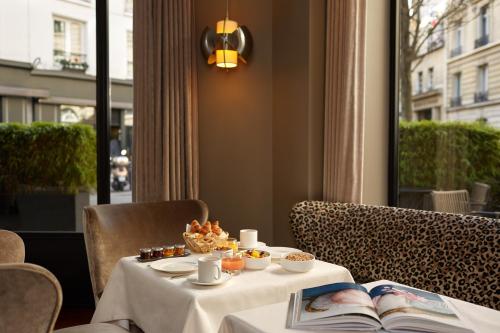 une table avec de la nourriture et un livre dans l'établissement Le Pavillon des Lettres, à Paris