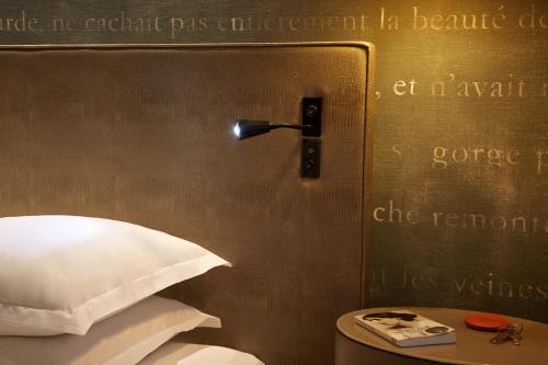 a sign that is on a wall next to a bed at Le Pavillon des Lettres - Small Luxury Hotels of the World in Paris
