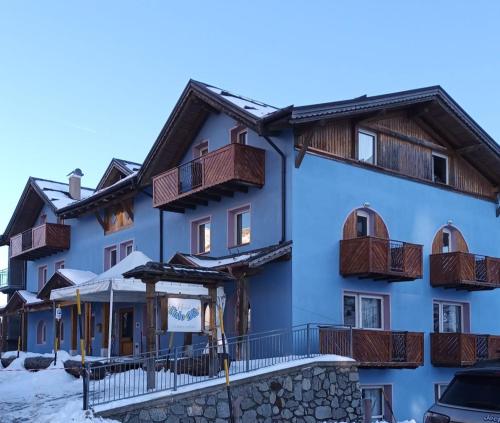 a building with wooden balconies in the snow at Hotel Cielo Blu in Passo del Tonale