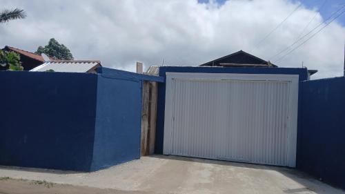 une clôture bleue avec une porte de garage blanche dans l'établissement Cabana 01, à Imbituba