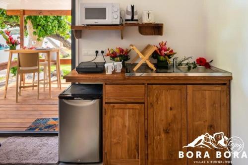 a kitchen with a sink and a counter with a microwave at Matira Beach Raitea 2 in Bora Bora
