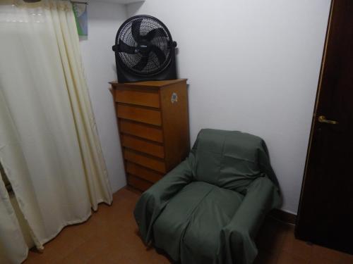 a room with a green chair with a fan on a dresser at Departamento Paz in Tandil