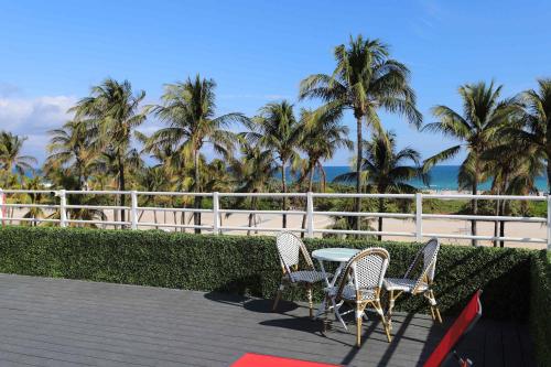 a table and chairs on a patio with palm trees at Rooftop Retreat on Ocean Drive with Beach View in Miami Beach