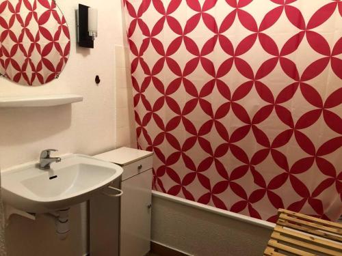 La salle de bains est pourvue d'un lavabo et d'un mur rouge et blanc. dans l'établissement Appartement 2 pièces PORT LA NOUVELLE PN210-036, à Port-la-Nouvelle