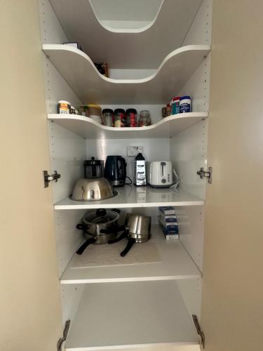a kitchen pantry with white shelves and appliances at Sunny House with 5 Bedrooms(near airport) in Christchurch