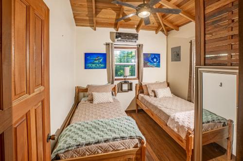 two beds in a room with a ceiling fan at 2 Coco Locos at Sunset in Seine Bight Village