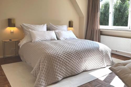 a bedroom with a bed with a white comforter and a window at Landhaus Meerbusch bei Düsseldorf in Meerbusch
