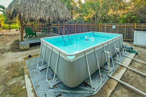 a hot tub in a backyard with a thatch roof at 2 Coco Locos at Sunset in Seine Bight Village
