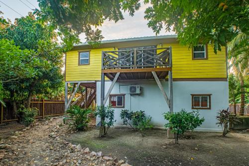 a yellow and white house with trees in front of it at 2 Coco Locos at Sunset in Seine Bight Village