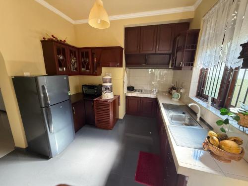 una cucina con mobili in legno e un frigorifero in acciaio inossidabile di Villa 74 a Negombo