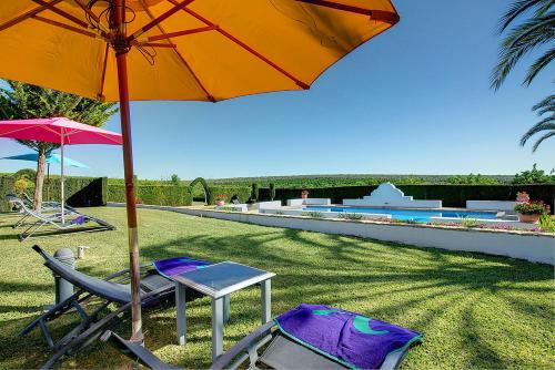 two chairs and an umbrella next to a swimming pool at Reservaloen Hacienda las Marciagas in Benacazón