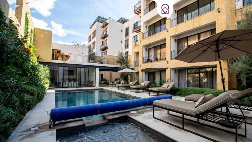 a swimming pool with chairs and an umbrella next to a building at Modern loft with luxury amenities in San Miguel in San Miguel de Allende