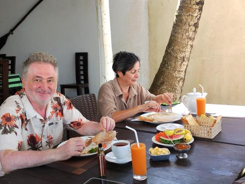 a man and woman sitting at a table eating food at Happy Beach Resort in Unawatuna