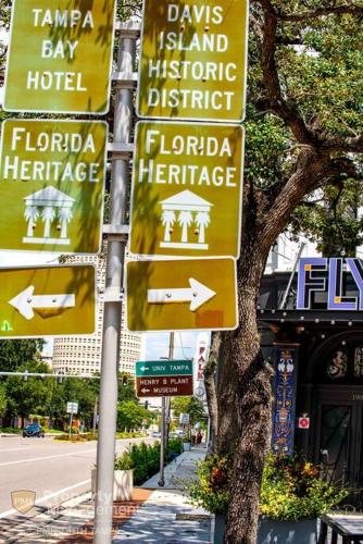 a bunch of street signs on a pole at Can't Buy Me Love - U of Tampa Flat in N Hyde Park in Tampa