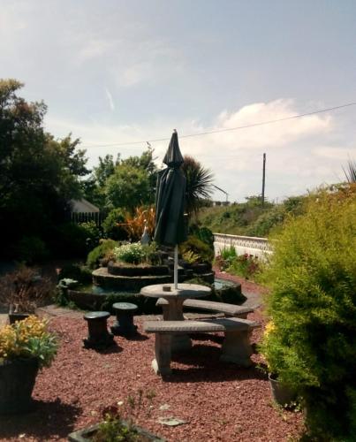 a garden with a bench and an umbrella at Melrose Bed and Breakfast in Clonakilty