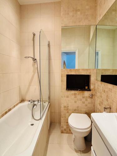 a bathroom with a toilet and a tub and a sink at Cosy & Modern in London