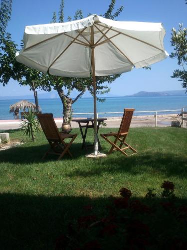 a table and two chairs under an umbrella near the beach at Evoikos beach & resort in Livanátai