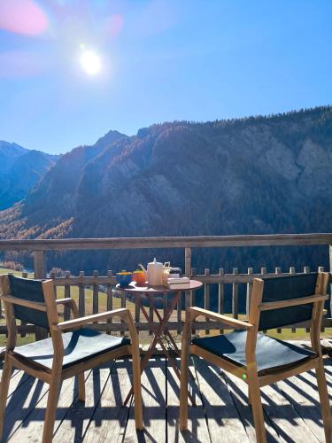 une table et deux chaises sur un balcon avec vue dans l'établissement Authentique chalet du Queyras - Saint Véran - Parc naturel du Queyras, à Saint-Véran