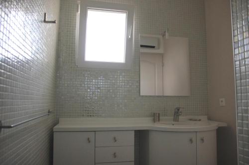 une salle de bain blanche avec un lavabo et une fenêtre dans l'établissement Les Lavandes du Moulin, à Puissalicon