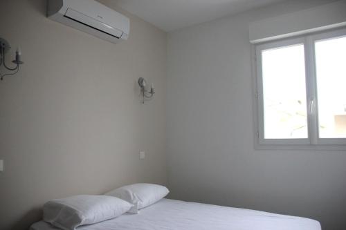 une chambre blanche avec un lit et une fenêtre dans l'établissement Les Lavandes du Moulin, à Puissalicon