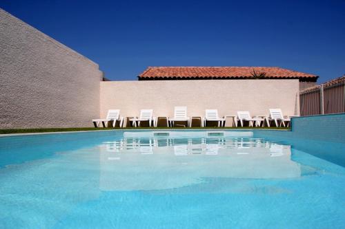 - un groupe de chaises blanches et une piscine dans l'établissement Les Lavandes du Moulin, à Puissalicon