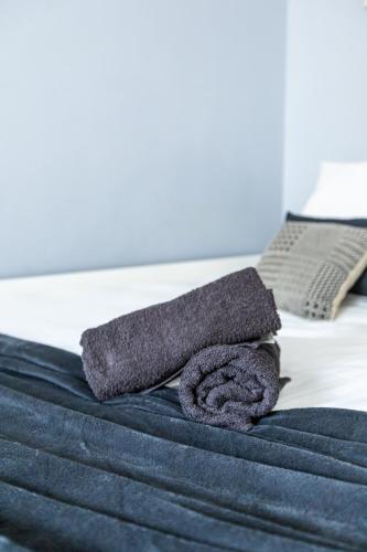 - une serviette grise au-dessus du lit dans l'établissement Le Clair & Spacieux - Parking - 15 min Paris, à Bois-Colombes