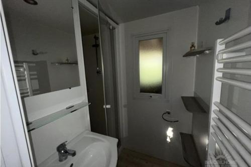 une salle de bain blanche avec un lavabo et un miroir dans l'établissement Mobile home CAMPING LES MATHES 8 personnes, aux Mathes