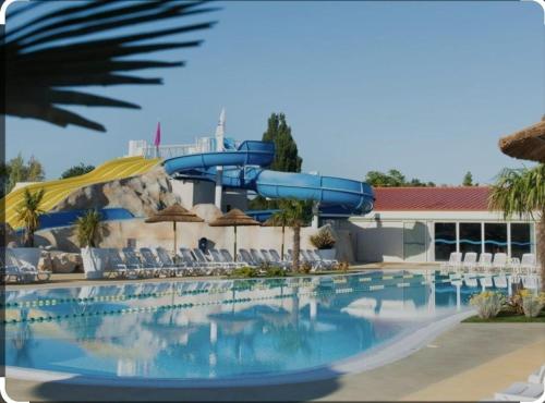 une piscine avec un toboggan aquatique dans un complexe hôtelier dans l'établissement Mobile home CAMPING LES MATHES 8 personnes, aux Mathes