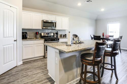 a kitchen with white cabinets and a counter with bar stools at 13 Mi to Baton Rouge Family-Friendly Home in Zachary
