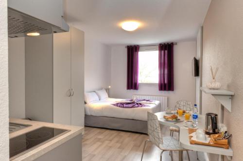 una piccola camera con letto e tavolo e una cucina di City Résidence Strasbourg Centre a Strasburgo