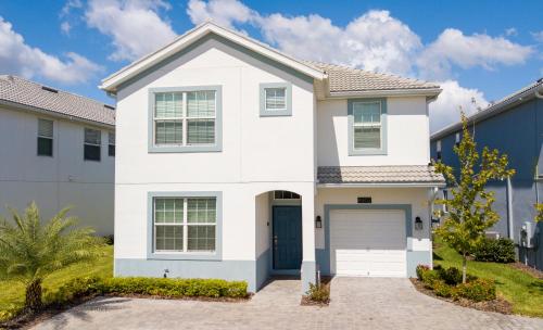 a white house with a garage at Storey Lake Pool Home with Resort Amenities near DISNEY in Kissimmee