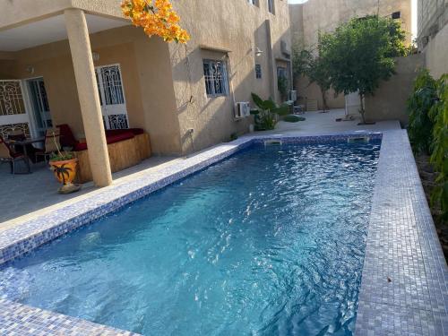 a swimming pool in front of a house at Maison de vacances in Mbour