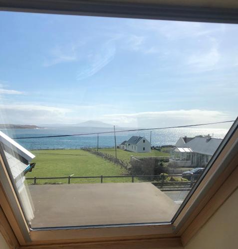 a window in a room with a view of the ocean at Teach Cruachan Large-Group Holiday Home in Dooagh