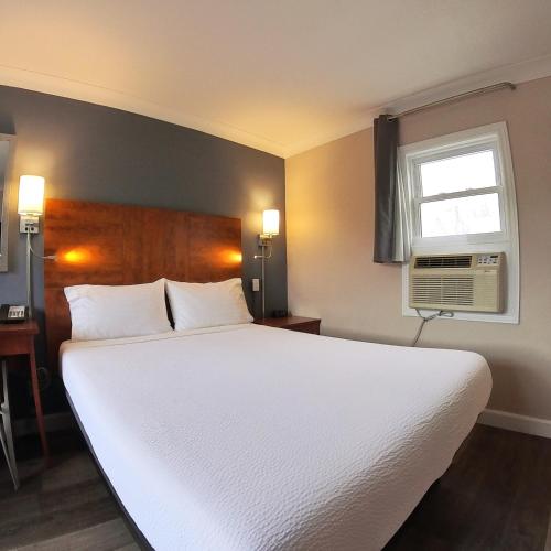 a bedroom with a large white bed and a window at Moonlight Inn and Suites Sudbury in Sudbury