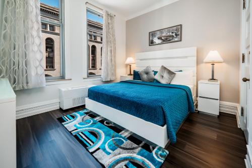 a white bedroom with a blue bed and windows at Congress Plaza Hotel Chicago in Chicago