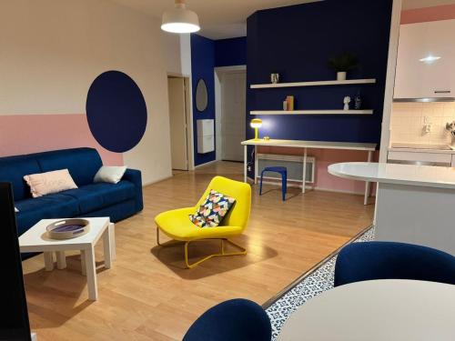 un salon avec un canapé bleu et un fauteuil jaune dans l'établissement Klein, à Clermont-Ferrand