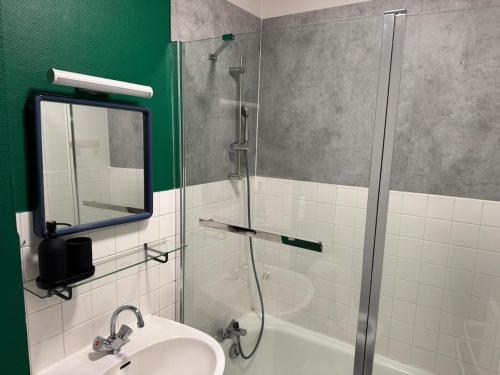 une salle de bain avec une douche, un lavabo et un miroir dans l'établissement Klein, à Clermont-Ferrand