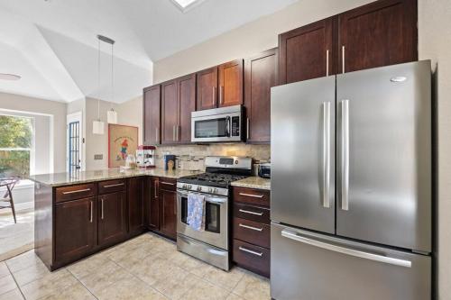 a kitchen with stainless steel appliances and wooden cabinets at Artist Retreat at Cypress Creek - Hotub - Sleeps 9 in Cedar Park