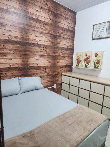 ein Schlafzimmer mit einem weißen Bett und einer Holzwand in der Unterkunft Casa no coração de Maricá in Maricá
