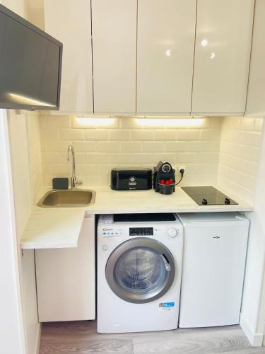une cuisine avec une machine à laver et un évier dans l'établissement Cute studio - Canal Saint Martin, à Paris
