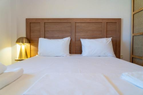 a large white bed with two pillows and a lamp at Cookoo Villas in Kriopigi