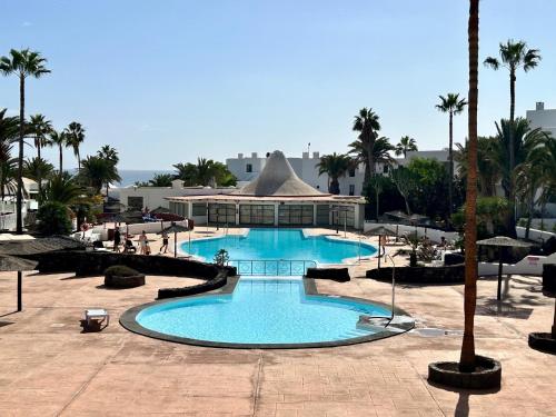 a large swimming pool in a resort with palm trees at Villa Irene Lanzarote en Costa Teguise en complejo con piscina comunal in Costa Teguise